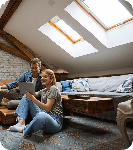 A couple looking at a tablet whilst sitting in their cosy converted loft space